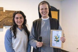 Scarleth berreicht Generaloberin Schwester Maria Thoma Dikow zum Dank ein selbst gesticktes Blumenbild. Foto: SMMP/Ulrich Bock